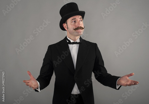Portrait of Victorian male with top hat. He has his hands out to the side, palms facing up and looking away from the camera