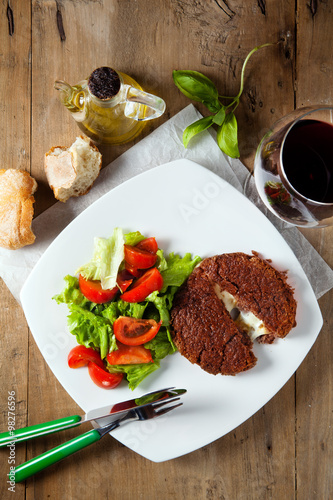 Burger cutlet stuffed with cheese inside of legumes with vegetab