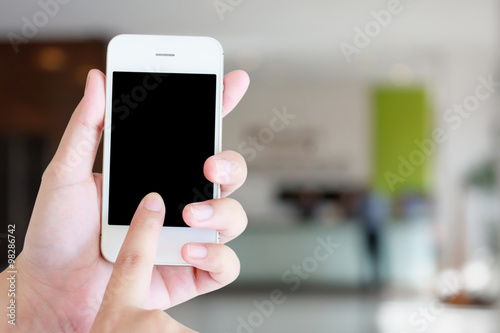Hand holding smartphone with hotel reception blur background