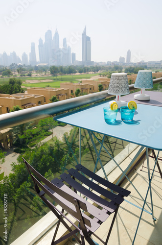 Ice cold drink with a slice of lemon with the dubai marina skyline view  from a balcony