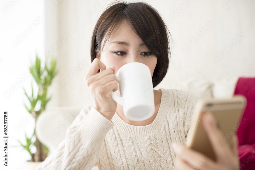 Women are looking at the mobile phone while drinking coffee Women are looking at the mobile phone while drinking coffee