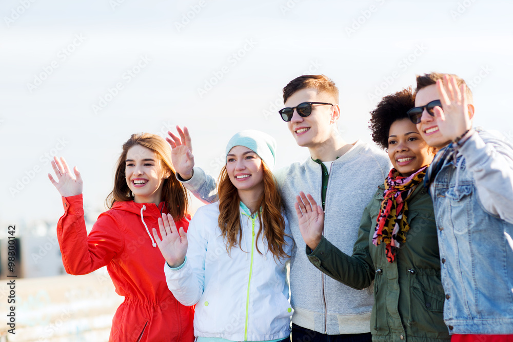 happy teenage friends waving hands on city street happy teenage friends waving hands on city street