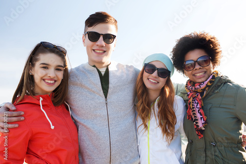 happy teenage friends in shades hugging outdoors © Syda Productions