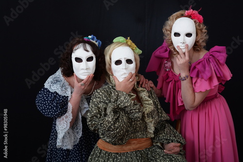 three girls in theatrical masks and dresses photo