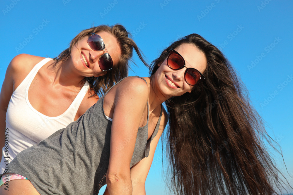 Two happy girls on a background of blue sky 