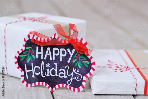 Still life with Happy Holidays sign and wrapped present boxes on the wooden board