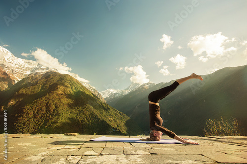 Young woman doing high level yoga asana exercise in mountains outdoor. Morning Fitness  headstand  Sport outdoors  Yoga tours