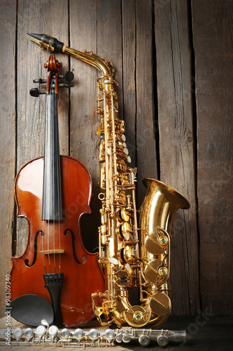 Musical instruments  saxophone  violin and flute with notes on wooden background