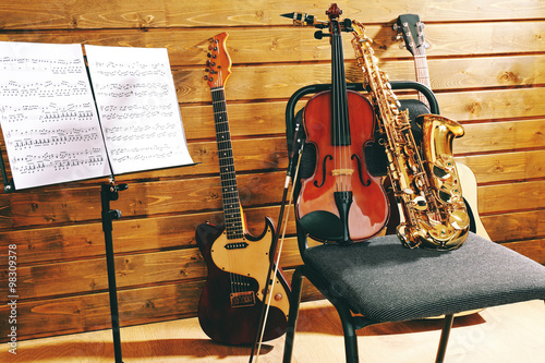 Musical instruments on a chair and note holder against wooden background