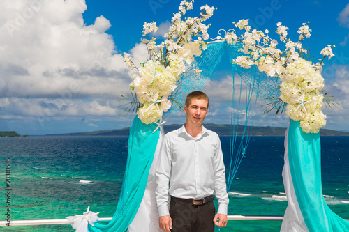 Wedding ceremony on a tropical beach in blue.The groom waits for photo