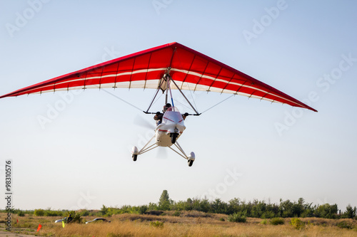 Obraz na płótnie Motorized hang glider soaring in the blue sky