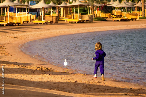 child running after a bird on the shore of the sea lagoon photo