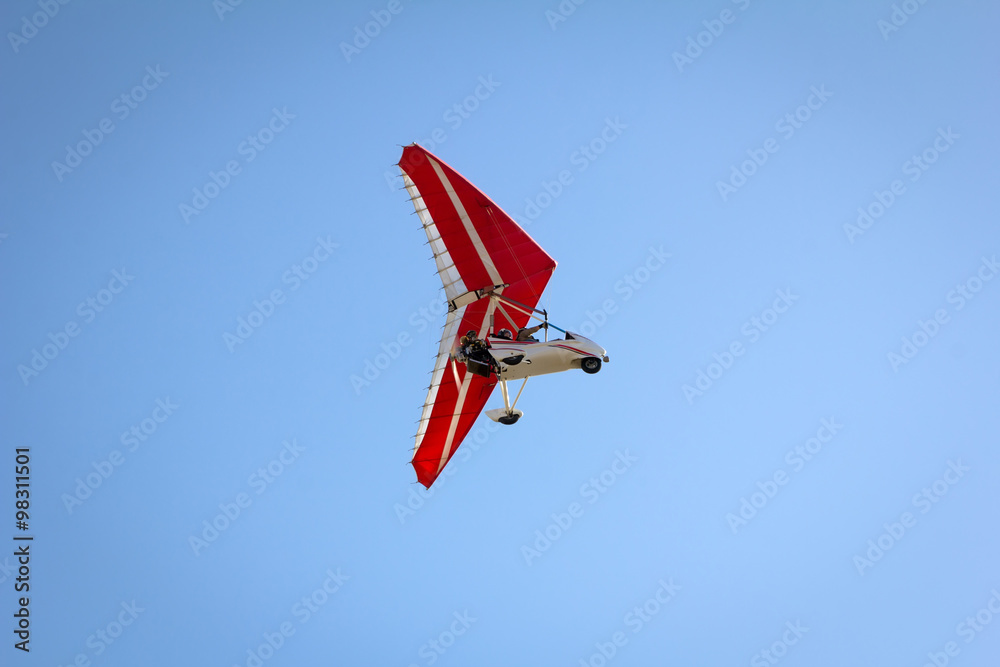 Motorized hang glider soaring in the blue sky Motorized hang glider soaring in the blue sky