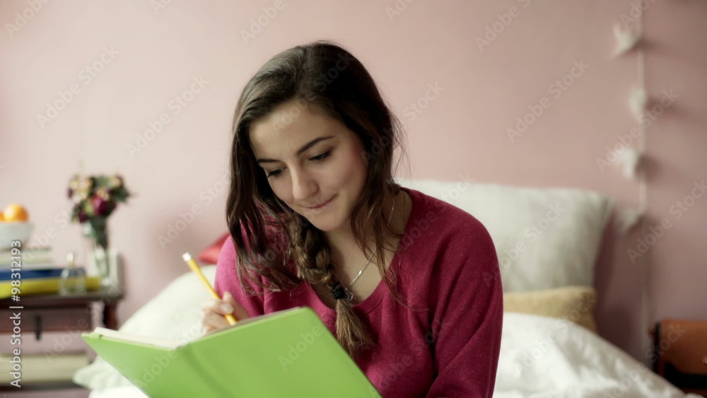 Teenage girl writing in her diary and smiling to the camera
Teenage girl writing in her diary and smiling to the camera