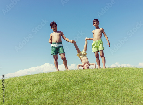 Brothers playing upside down on green meadow