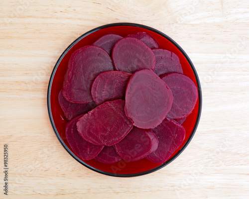 Sliced beets on a red plate atop table