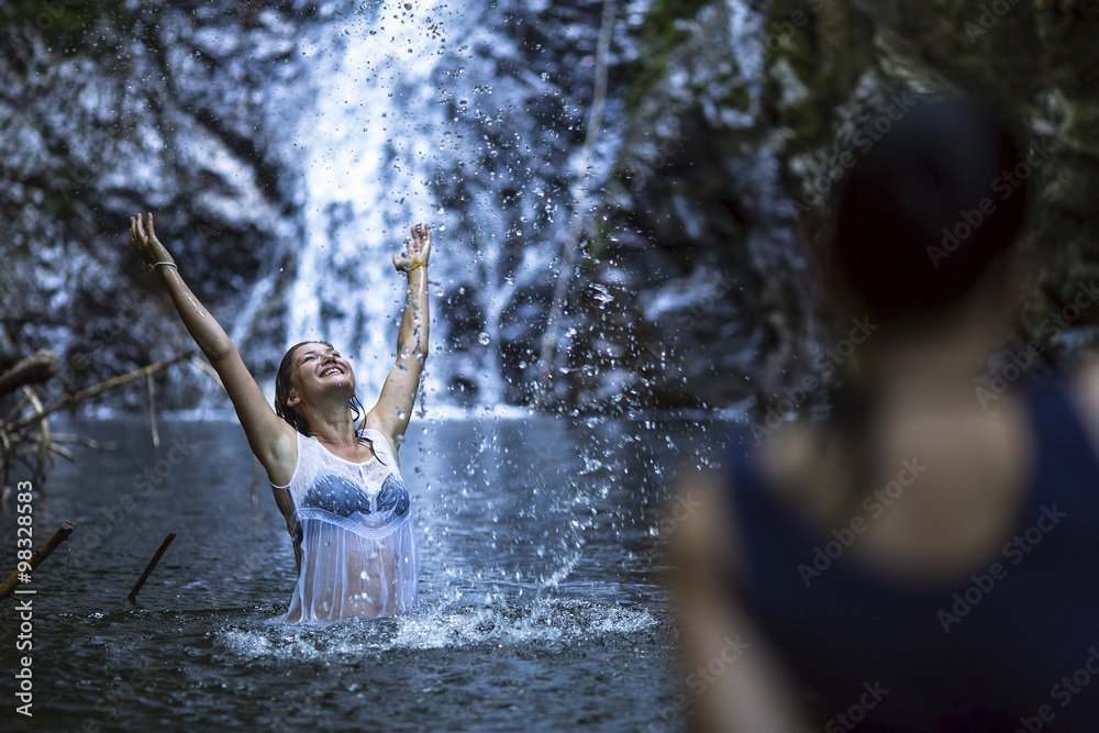 Fototapeta premium An attractive young woman bathing near the waterfall.