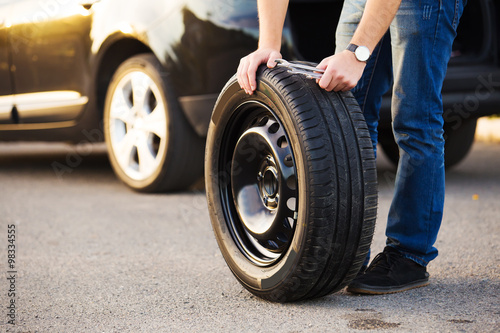 Sad and depressed man sitting near car with punctured tire