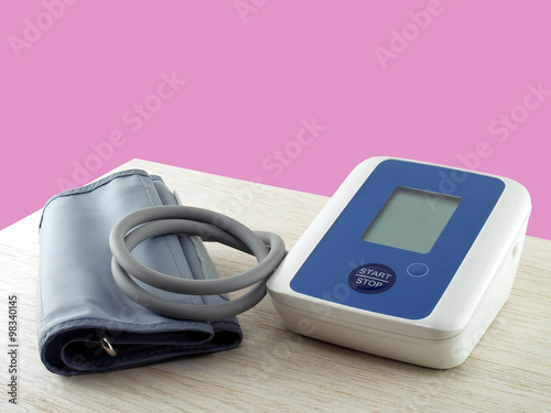 portable electronic blood pressure monitor on desk corner isolated on pink