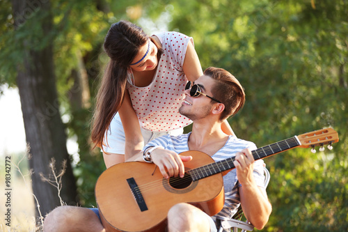 Attractive couple playing guitar, outdoors