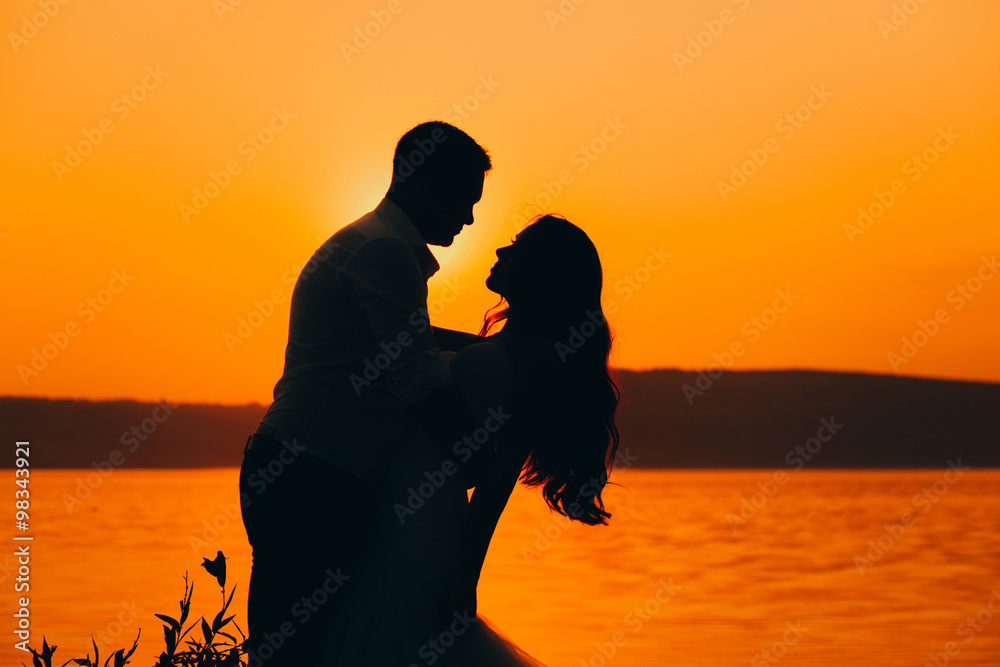 a happy married couple posing on the beach during sunset