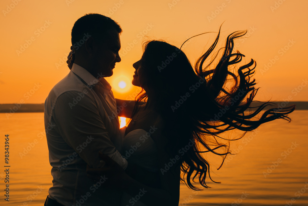 a happy married couple posing on the beach during sunset