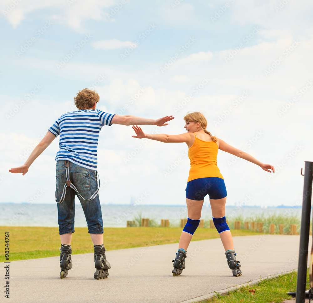 Young couple on roller skates riding outdoors Young couple on roller skates riding outdoors