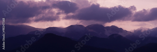 Silhouette of Mountains Above the Water under purple cloudscape clouds at sunset