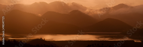 Silhouette of Mountains Above the Water under orange cloudscape clouds at sunset