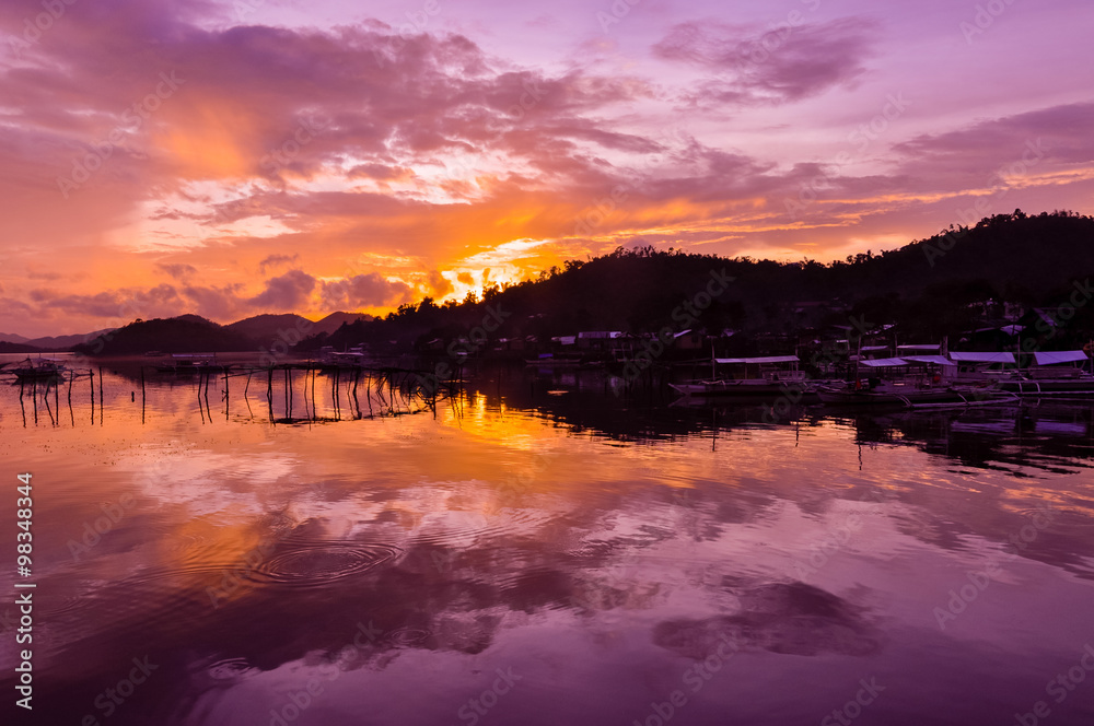 Pretty Pink orange Sky cloudscape over an island with reflection at Sunset on the Island of Coron