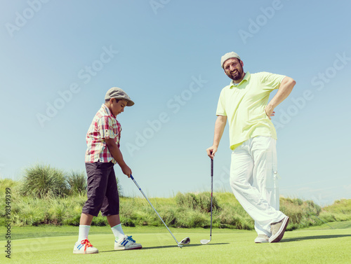 Father teaching son playing golf at club