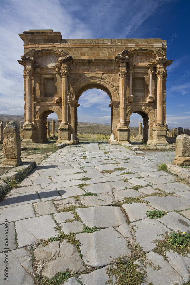 Algeria. Timgad (ancient Thamugadi or Thamugas). Paving stones of Decumanus Maximus street and 12 m high triumphal arch, called Trajan's Arch
