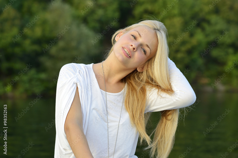 Portrait of beautiful young blond girl sitting in a boat and touching her hair Portrait of beautiful young blond girl sitting in a boat and touching her hair