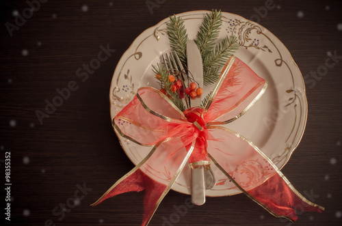 Christmas table place setting with christmas pine branches and plate, knife, fork and ribbon. Christmas holidays background.