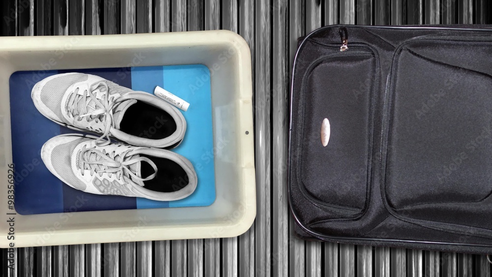 Various personal items from passengers pass by in bins on their way into the x-ray machine at an airport security checkpoint station.	