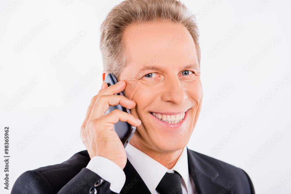A mature businessman with mobile phone and charming smile A mature businessman with mobile phone and charming smile