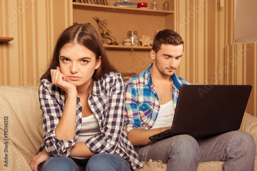 Young couple in quarel siting isolated in living room photo