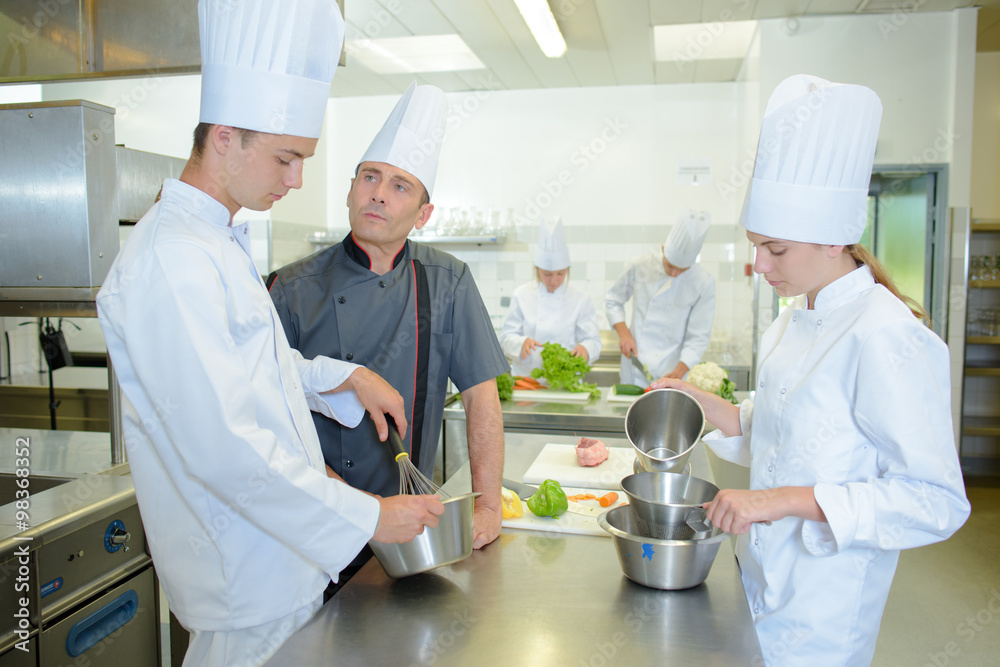 Trainee cooks under the supervision of a chef