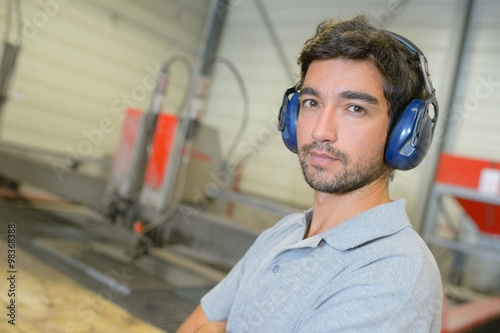 Tableau sur toile Portrait of man in factory, wearing earmuffs