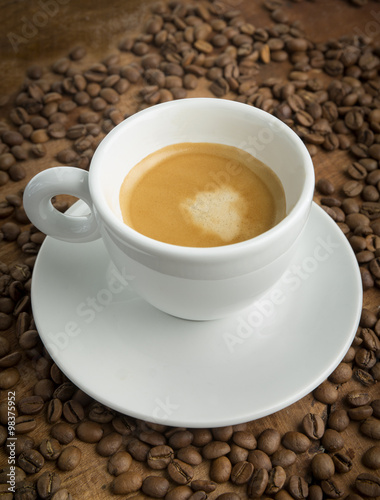 Cup of espresso on wooden table with coffee beans