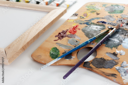 Art palette with paint and a brush on white background