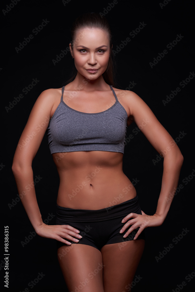 Beautiful young girl on a dark background is engaged in fitness