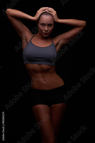 Beautiful young girl on a dark background is engaged in fitness © legull