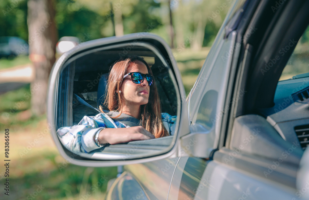 Reflection in side view mirror of woman driving car