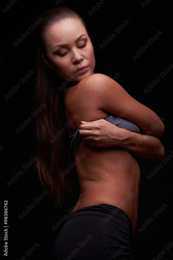 Beautiful young girl on a dark background is engaged in fitness Beautiful young girl on a dark background is engaged in fitness
