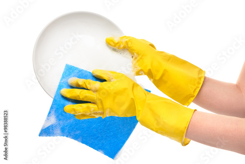 Close up of female hands in yellow protective rubber gloves washing white plate with blue rag against white background