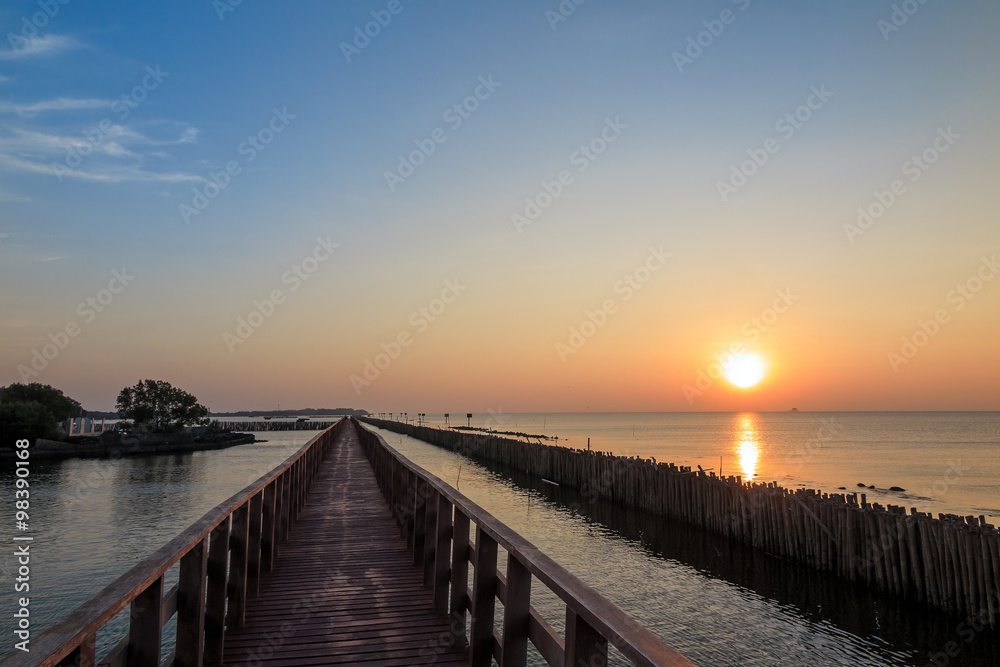 Wooden bridge to the sea with sunrise