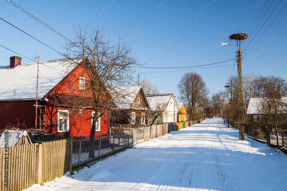 Drewniane wiejskie chaty przy drodze zasypanej śniegiem - obrazy, fototapety, plakaty 