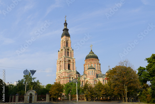 Cathedral of the Annunciation in Kharkov, surrounded by trees on the background of blue sky and light clouds. Front view. Daytime