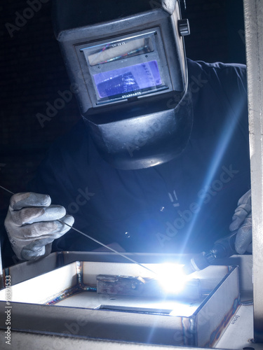 Skilled worker welding metal together in a welding factory